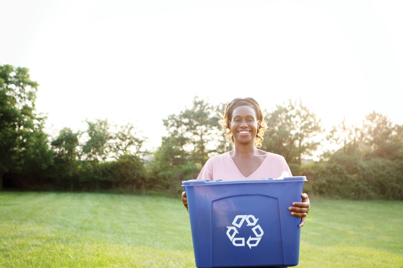 A woman holding a recycling container
