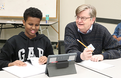 An older man helping a boy with his homework.