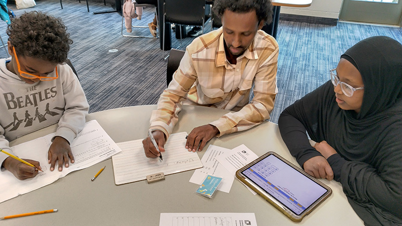 A man helping two kids with their homework.