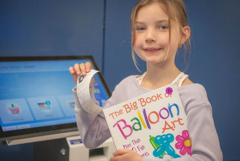 Girl holding a checkout slip after using her library card.