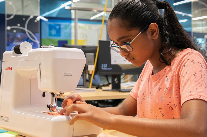 Girl using a sewing machine at a Dakota County Library iLAB.