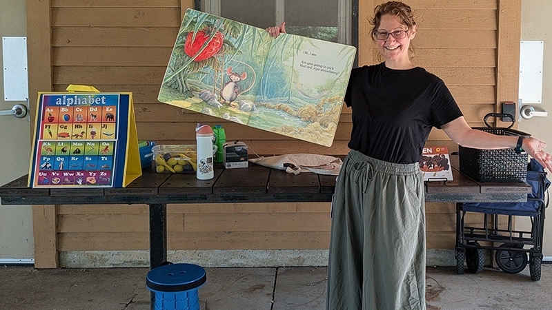 Librarian holding up at book at an outdoor Storytime.