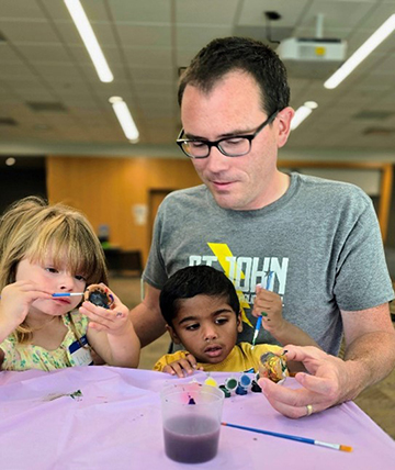 Adult male doing an art project with two kids.