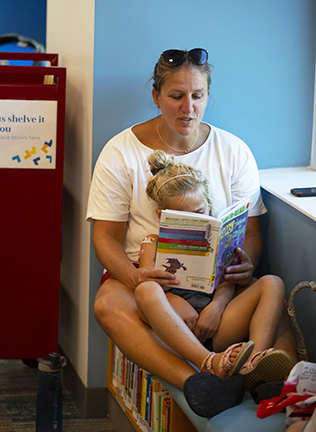 Kid and adult reading together in library.