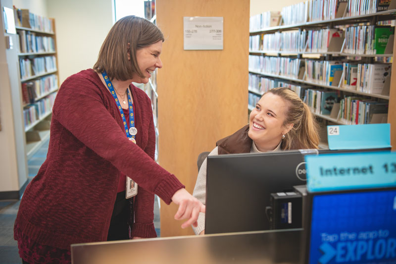 Dakota County Library staff helping a patron at a computer.