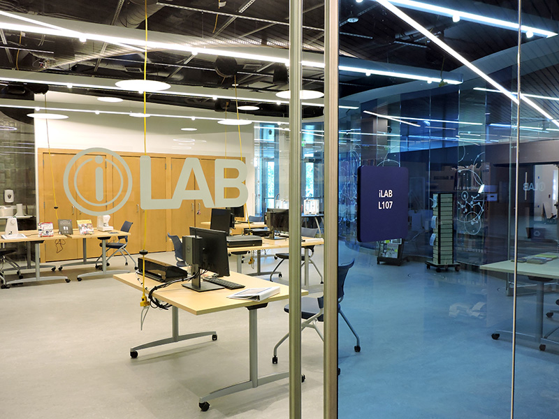 iLAB creative space on window showing desk and computer equipment. 