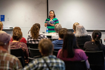 An author reading her book in front of a group of people. 
