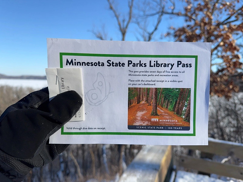 Gloved hand holding a MN Library Park Pass.