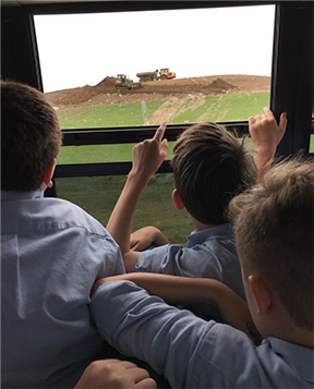 A picture of kids looking at a landfill outside of a bus.