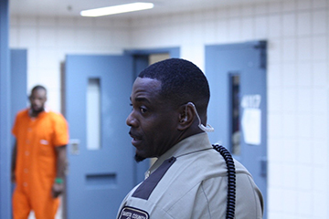 Correctional Deputy at the jail with an inmate in background.