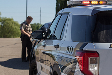 Squad car with Sheriff's Deputy in front performing a traffic stop.