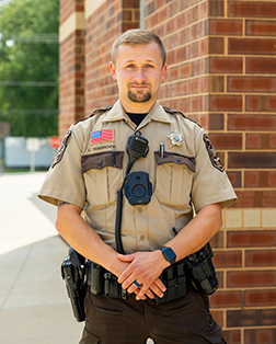 School Resource Officer in uniform standing in front of a building.