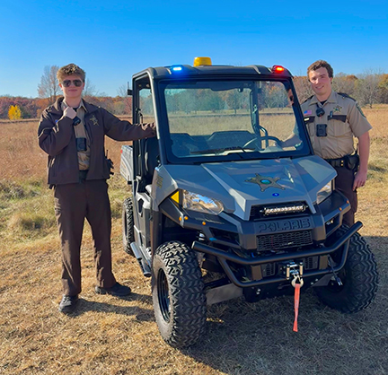 Two members of the parks, lakes, and trails unit standing near their ATV.