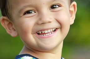 Young boy smiling with teeth showing.