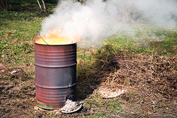 Picture of a burn barrel with smoke and flames.