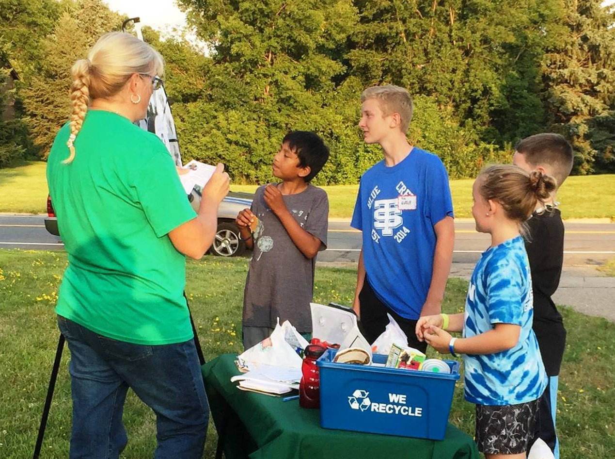 A woman teaching children how to recycle.