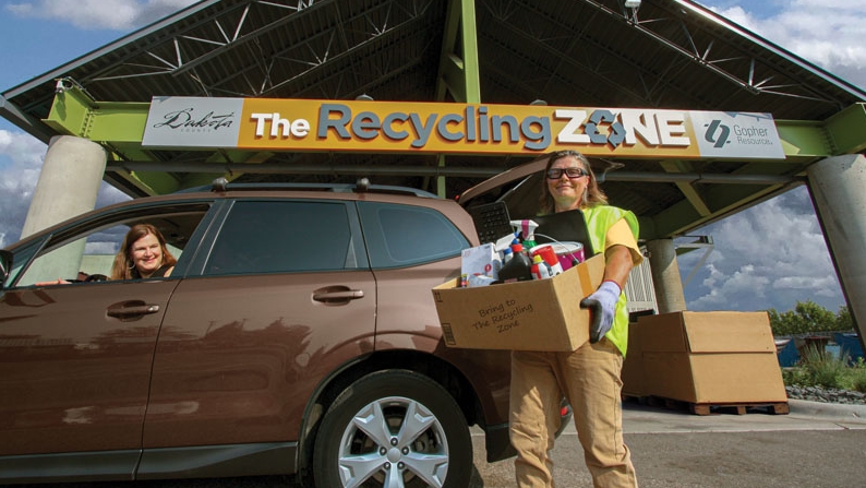 Recycling Zone staff removing hazardous waste from a parked vehicle.