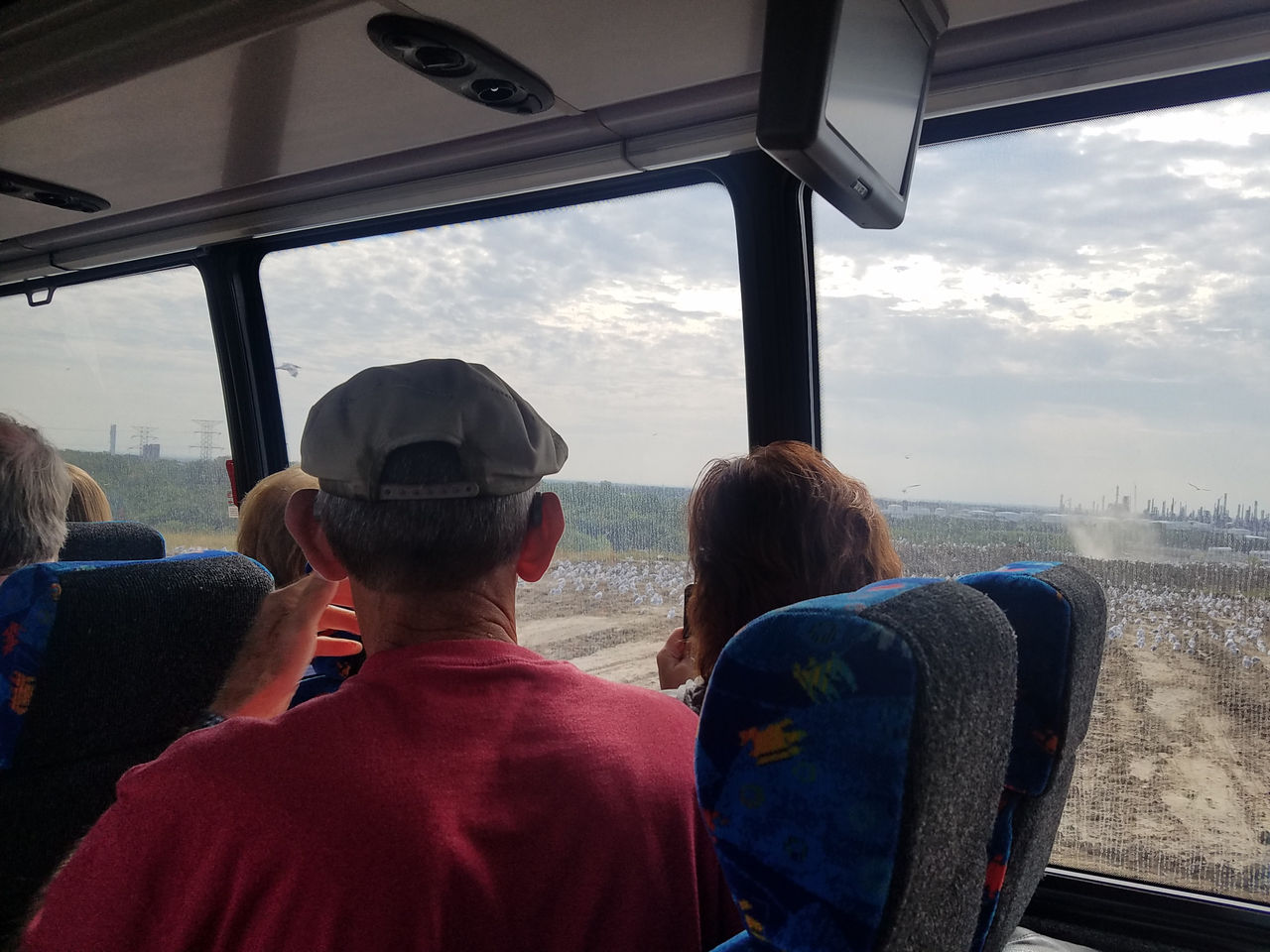 People looking out of a bus window at a landfill.
