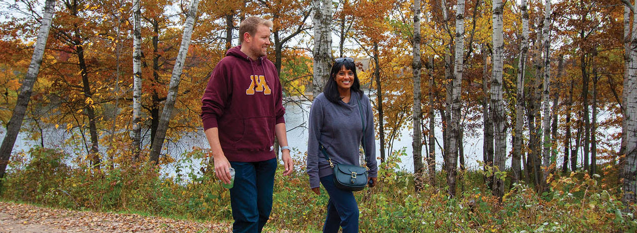 Two people walking down a fall trail.