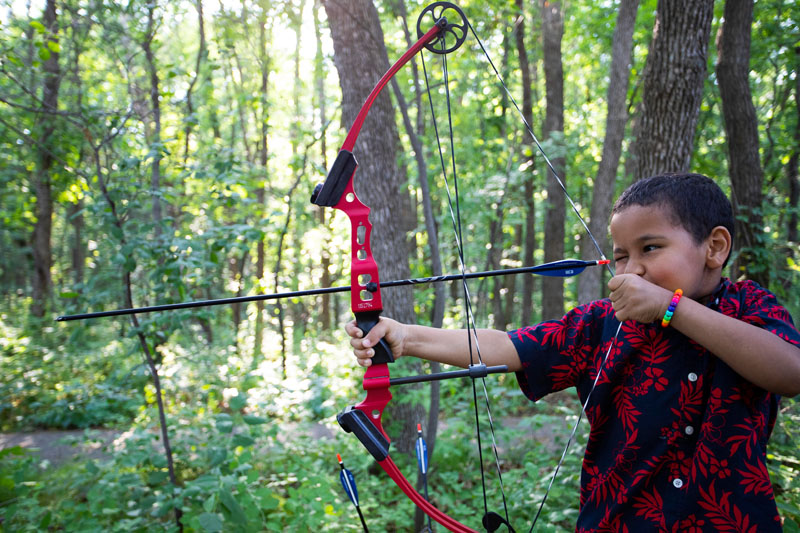 Boy drawing back his bowstring on the Archery Trail.
