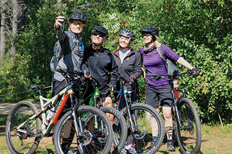 A group of mountain bikers stops for a selfie photo.