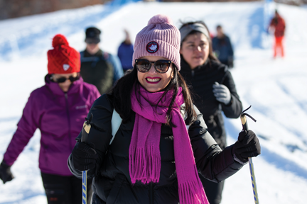 A smiling woman cross-country skiing.