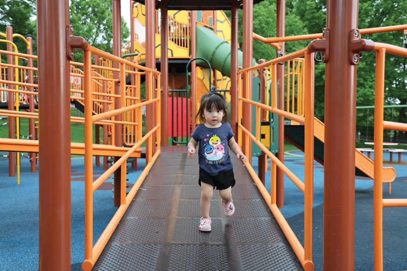 A child walks across a span of playground equipment.