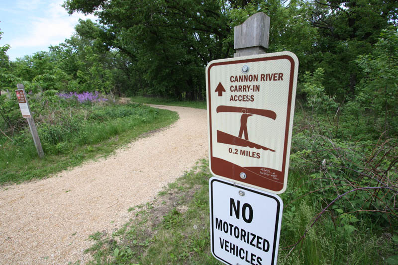 A sign standing at the edge of a grassy area.