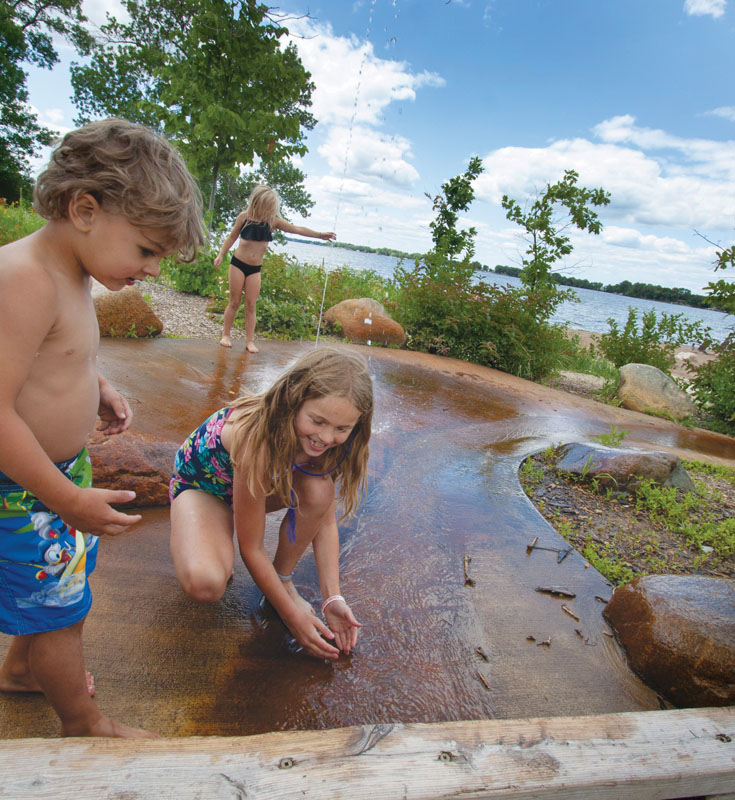 Three children playing with water at the splash pad