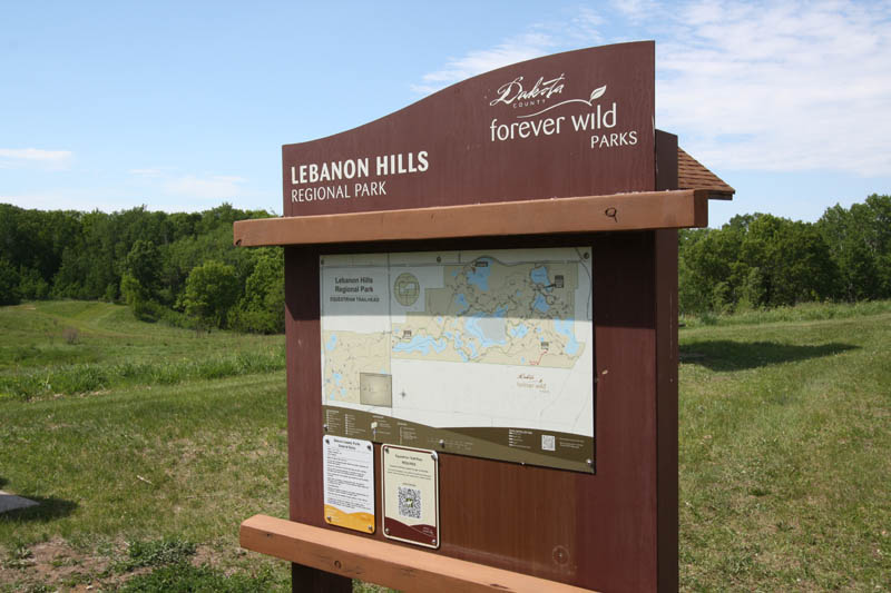 A sign standing at the edge of a grassy area.