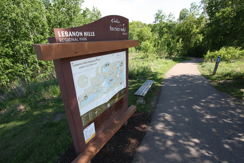A trailhead kiosk alongside a paved trail.