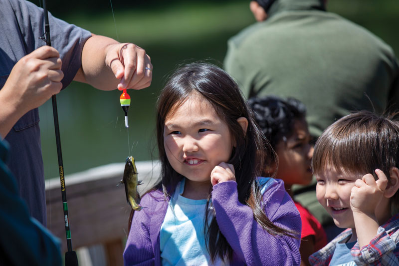Two children looking at a fish on a hook