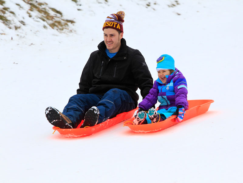 Man and child on sleds